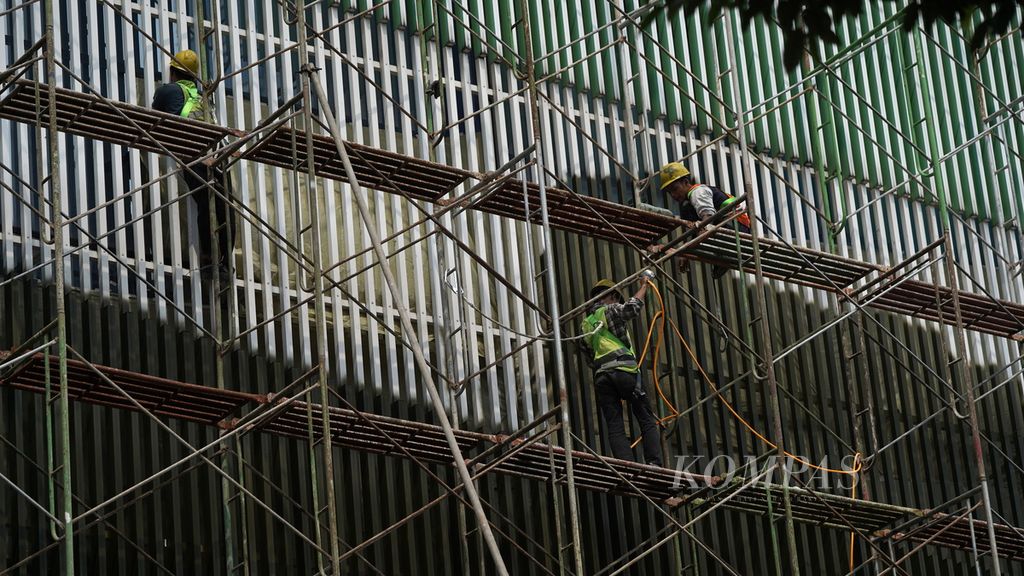 Pekerja merampungkan pengecatan kisi-kisi gedung bertingkat di Jalan Gatot Subroto, Jakarta Selatan, Senin (28/11/2022). Indonesia belum memiliki kepastian sistem pengupahan yang di dalamnya menyangkut upah minimum. 