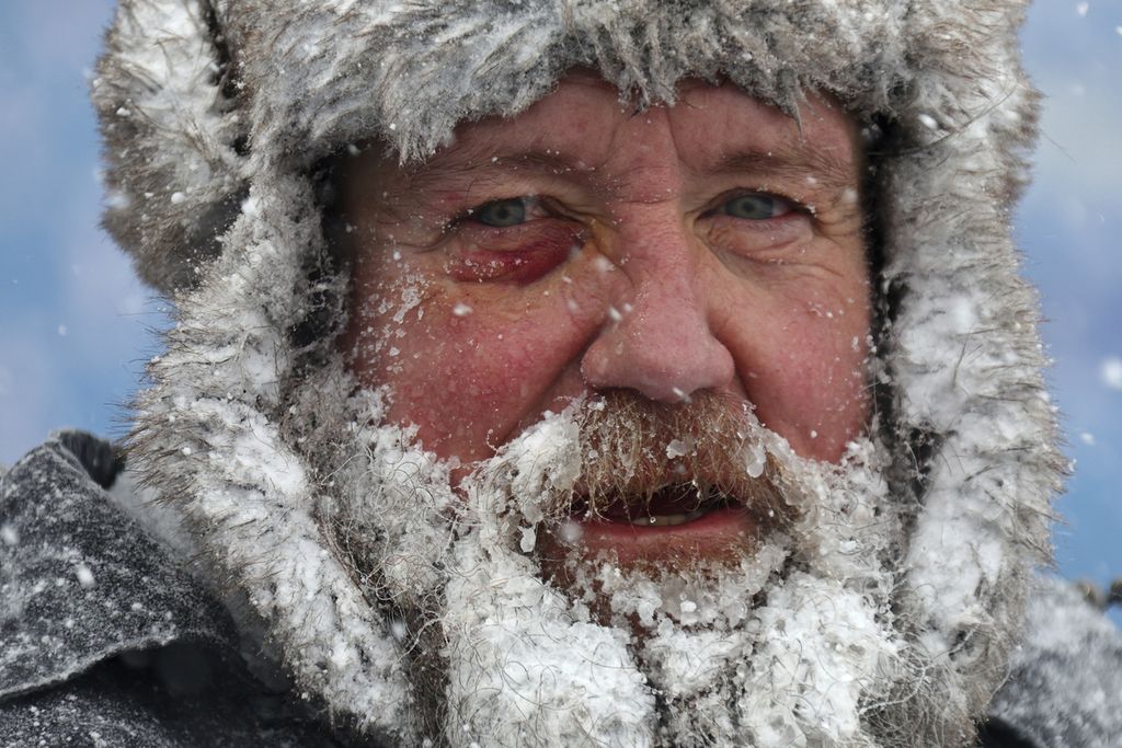 Salju menyelimuti sebagian wajah seorang pekerja yang membersihkan salju dari Stadion Highmark di Orchard Park, New York, Amerika Serikat, 14 Januari 2024. Saat ini, AS tengah dalam cengkeraman musim dingin ekstrem.  