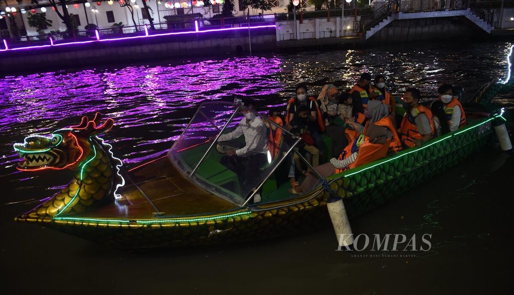 By boat, residents enjoy the colorful lights along the Kalimas River at the Achievement Park, Surabaya City, Tuesday (12/7/2022) night.