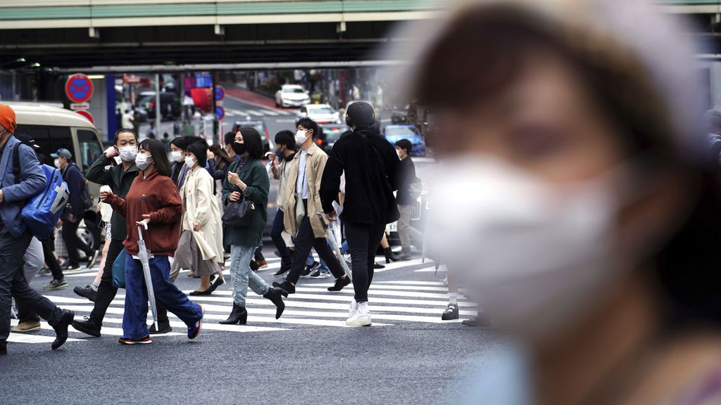 Orang-orang yang mengenakan masker pelindung saat melewati penyeberangan pejalan kaki di awal liburan Golden Week di Distrik Shibuya, Jepang, Kamis (29/4/2021). 