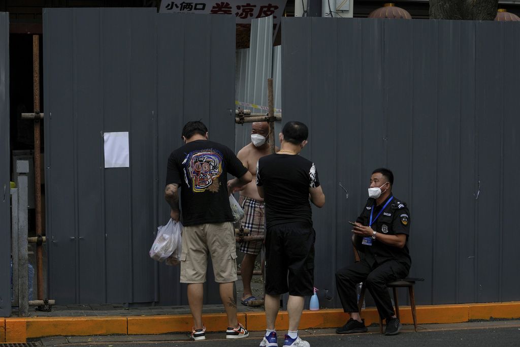 Seorang penjaga keamanan mencatat dan memantau petugas jasa antar di sebuah pemukiman di Beijing yang masih menjalani karantina. Foto diambil pada Minggu (26/6/2022).