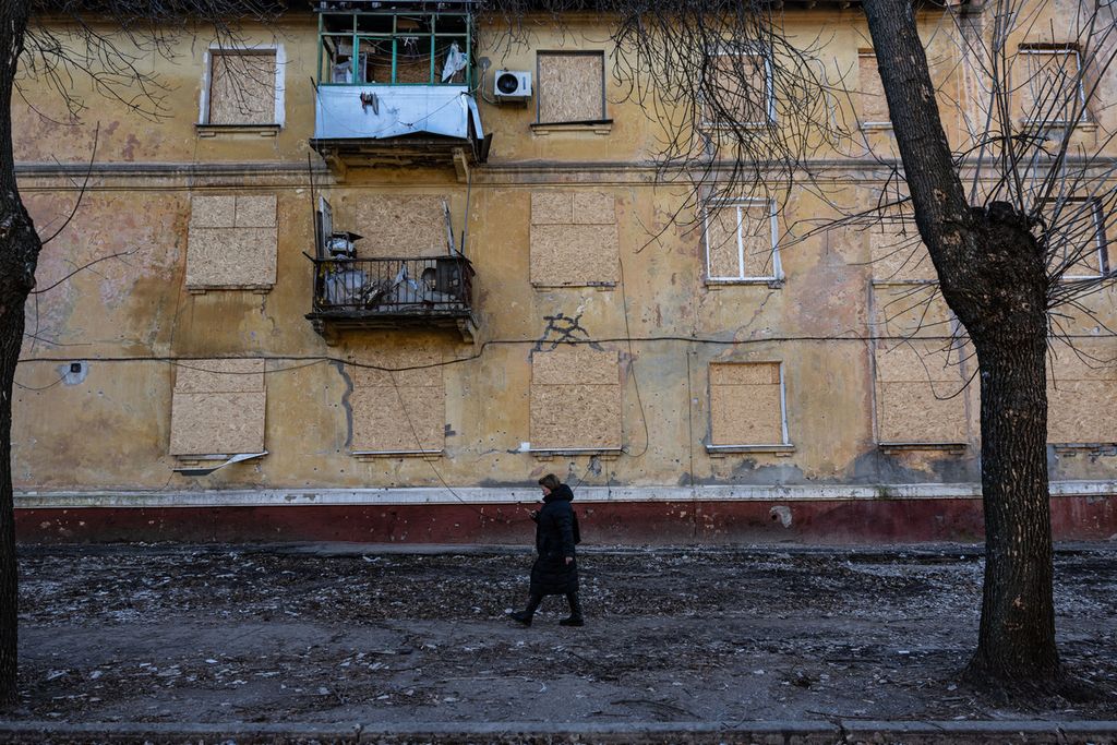 Seorang perempuan melintas di depan gedung yang rusak di Kramatorsk, Ukraina timur, Senin (19/12/2022). 