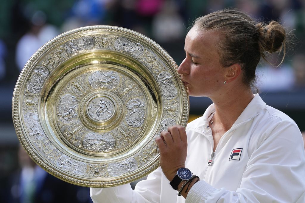 Petenis Ceko, Barbora Krejcikova, mencium trofi juara Wimbledon setelah mengalahkan petenis Italia, Jasmine Paolini, pada partai final di London, Sabtu (13/7/2024). 