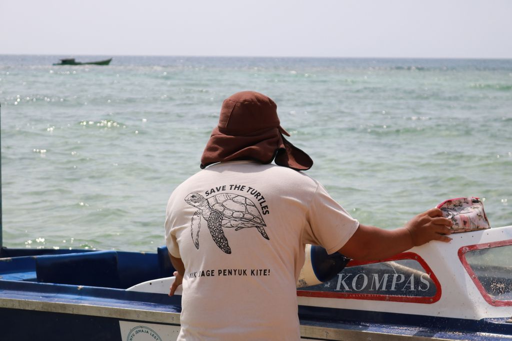 Ketua kelompok Penyu Jemaja Lestari Burhanudin (46) akan menjemput para wisatawan dari perahu yang tak dapat ke daratan karena kekayaan karang di Pantai Teluk Sadang, Kabupaten Anambas, Kepulauan Riau, Jumat (26/7/2024). Burhanudin telah memperjuangkan pelestarian penyu-penyu ini sejak 2018. 