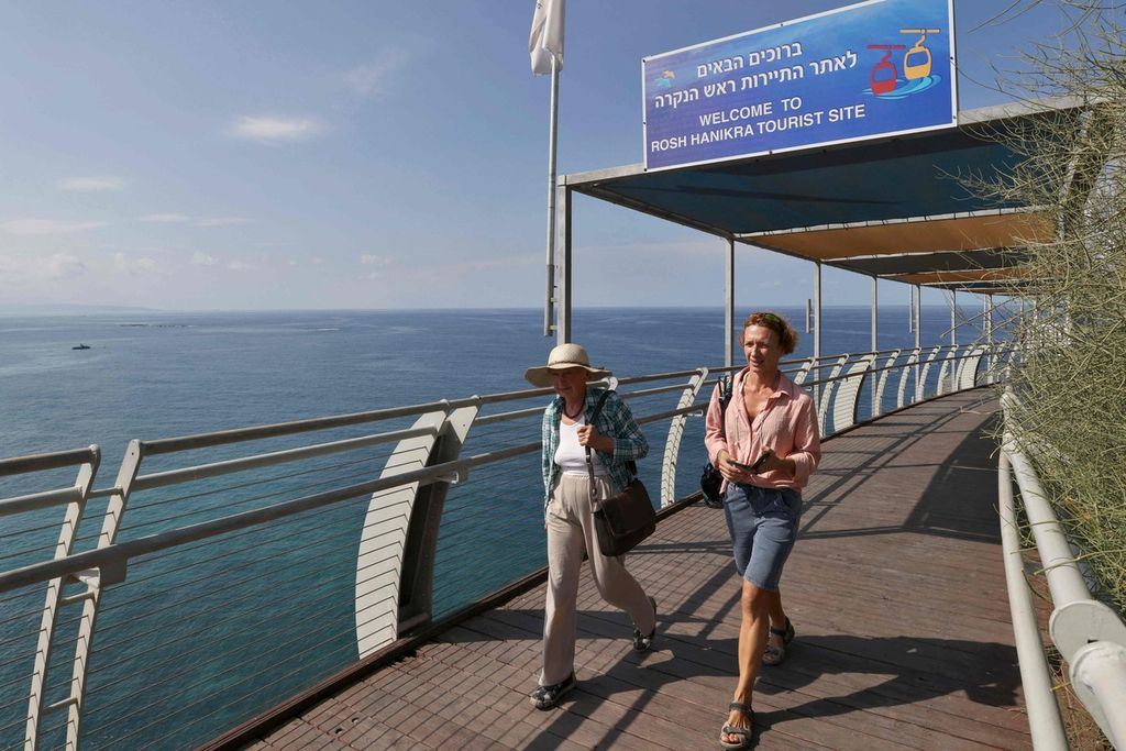 Foto tanggal 7 Oktober 2022 ini memperlihatkan turis berjalan di tepi laut di area perbatasan Lebanon-Israel, Rosh Hanikra, dengan pemandangan ke arah Laut Tengah. 
