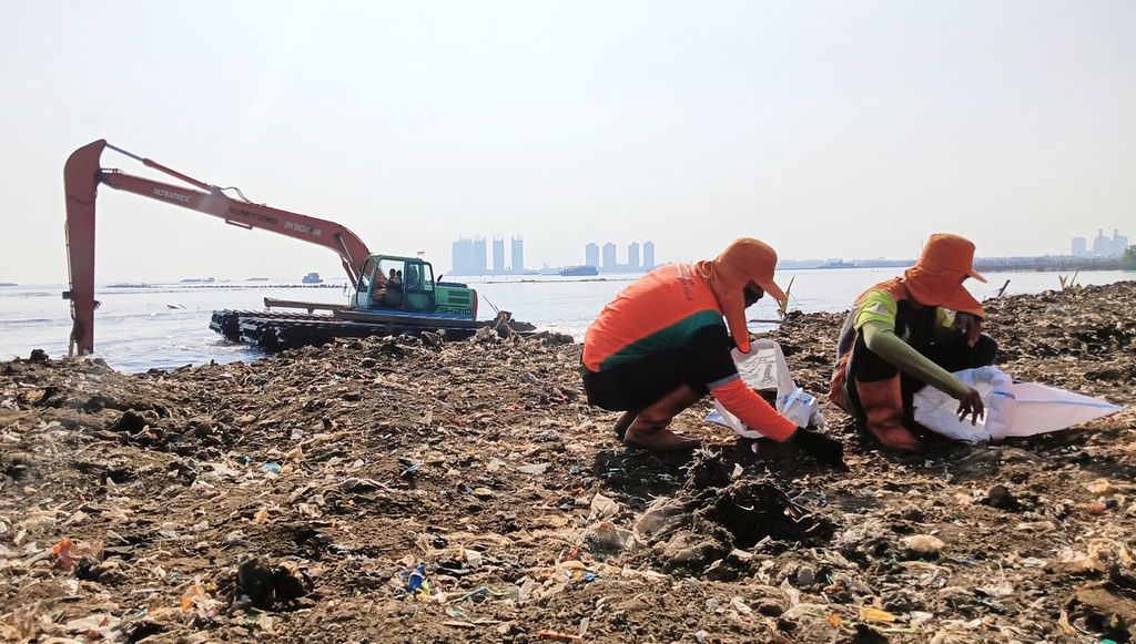 Dua petugas mengambil sampah di sekitar kawasan pesisir Muara Kali Adem, Penjaringan, Jakarta Utara, Kamis (7/9/2024).