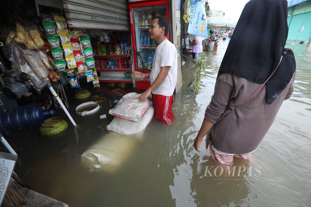 Warga memasang tanggul dari karung pasir di sisi depan kiosnya yang tergenang banjir rob di kawasan Muara Angke, Pluit, Penjaringan, Jakarta Utara, Senin (16//11/2020). 