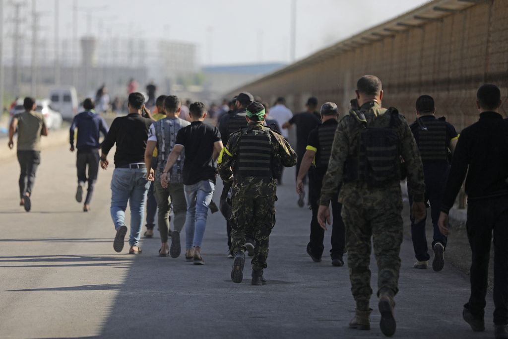  Sejumlah warga Palestina bercampur dengan anggota Brigade Al-Qassam, sayap militer kelompok Hamas, berjalan di Erez, Israel, salah satu titik ”penyeberangan” yang berhasil disusupi, Sabtu (7/10/2023).  