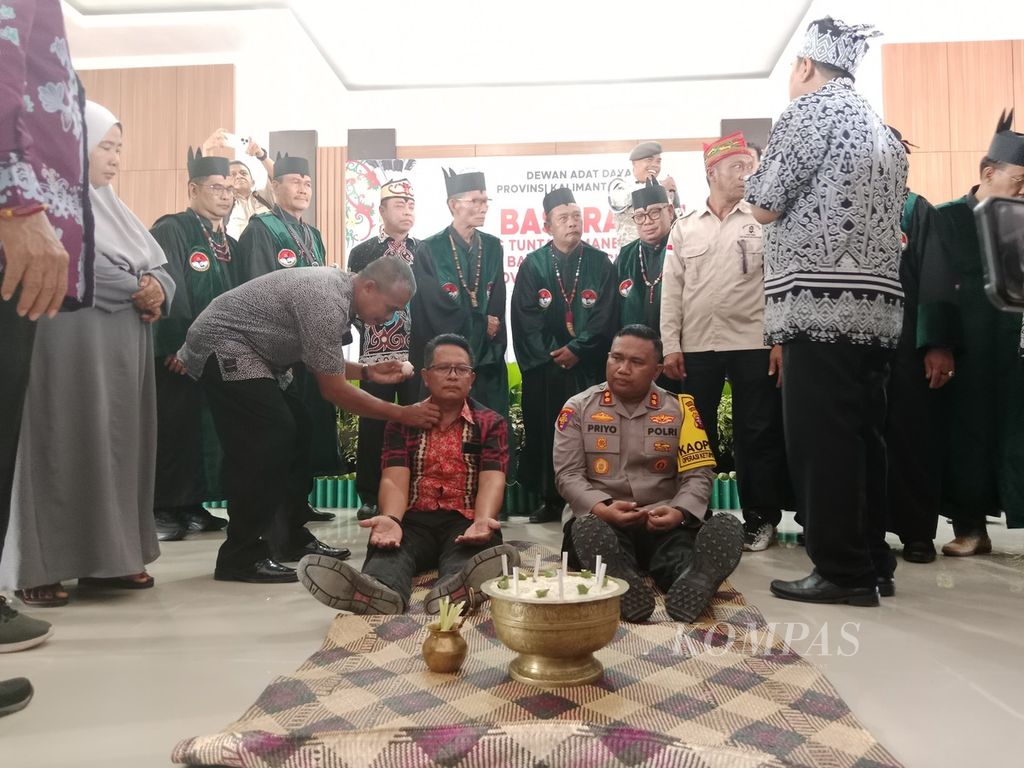 Perwakilan Polda Kalteng dan PT HMBP saat diberi upacara adat di sela-sela sidang adat dayak di Kota Palangka Raya, Kalteng, Jumat (19/4/2024). Keduanya didenda ratusan juta rupiah.