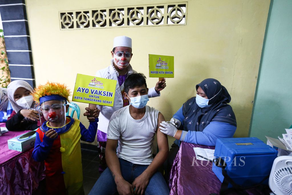 Badut mendampingi warga yang menerima suntikan vaksin Covid-19 dalam kegiatan gebyar vaksinasi Kota Tangerang di RW 004, Sudimara Pinang, Kecamatan Pinang, Kota Tangerang, Banten, Selasa (14/9/2021). 
