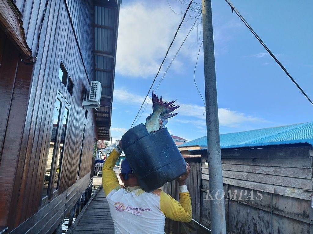 Agus (54) membawa ikan tangkapannyamenuju pasar ikan di Desa Talisayan, Kecamatan Talisayan Kabupaten Berau, Kalimantan Timur, Selasa (27/2/2024).