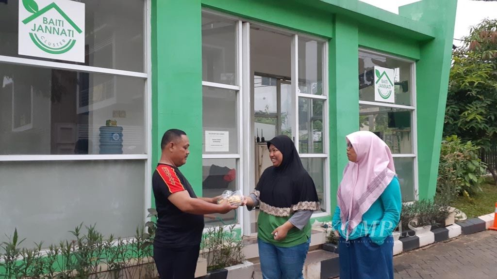 Yaya Auliyati (tengah) dan Mutiara Adinda (kanan) sedang memberi makanan dan minuman untuk buka puasa kepada petugas Satpam kluster Baiti Jannati kompleks perumahan Villa Ilhami Karawaci, Tangerang, Banten, Minggu (19/5/2019)