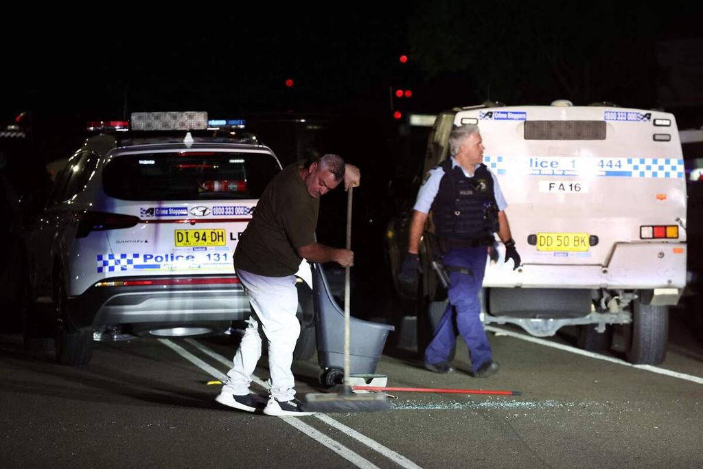 Residents clean up the broken glass of a police car vandalized during the riot outside the Asyrian Orthodox Church of Christ the Good Shepherd building in Wakeley, New South Wales, on Monday (15/4/2024).
