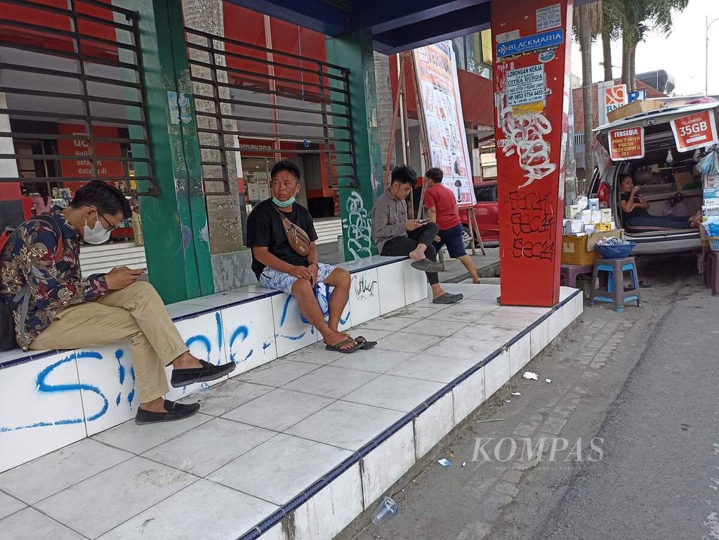 Warga beraktivitas di sebuah halte di Jalan Iskandar Muda, Medan, Sumatera Utara, Jumat (15/7/2022). Pemerintah Provinsi Sumut akan segera mewajibkan vaksinasi dosis lanjutan bagi warga yang beraktivitas di sarana publik. 