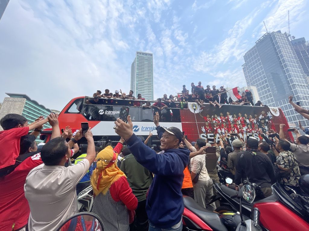 Warga menyambut kedatangan bus yang mengangkut rombongan tim sepak bola Indonesia U-22 dalam acara Kirab Juara di depan Bundaran HI, Jakarta, Jumat (19/5/2023). 