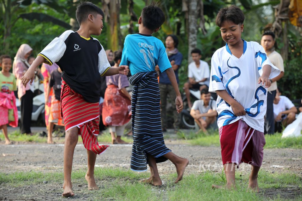 Anak-anak dengan mengenakan kain tenun bersiap mengikuti permainan tradisional selodor di Desa Pringgasela Selatan, Kecamatan Pringgasela, Lombok Timur, Nusa Tenggara Barat, Minggu (17/12/2023).