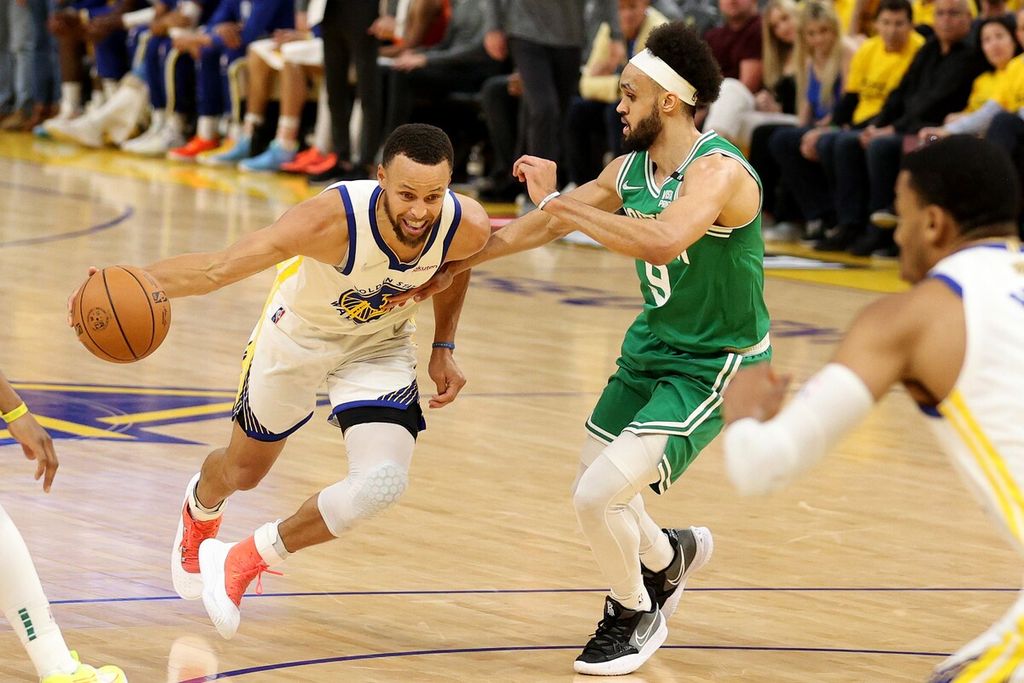 Pemain Golden State Warriors Stephen Curry mendribel bola melewati pemain Boston Celtics Derrick White pada laga kedua final NBA di Chase Center, San Francisco, Senin (6/6/2022) WIB. Warriors menang dengan skor 107-88 sehingga kedudukan menjadi 1-1.