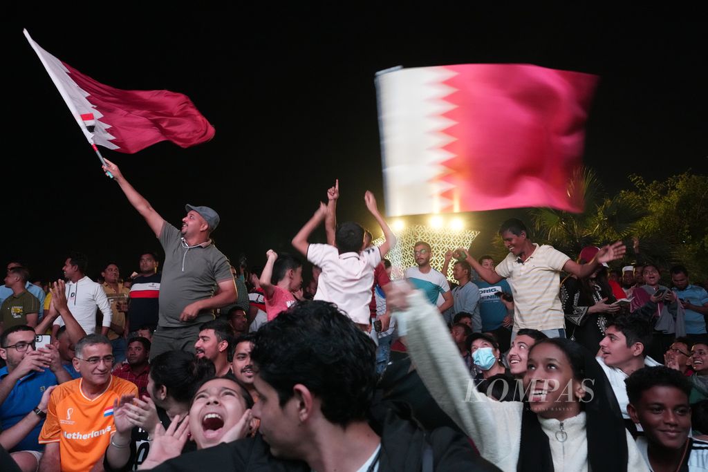 Residents of Doha, Qatar, watch the opening match of the 2022 World Cup between hosts Qatar against Ecuador through a big screen in the tourist area of Corniche Beach, Sunday (20/11/2022). In that match, Qatar lost 0-2 to Ecuador.