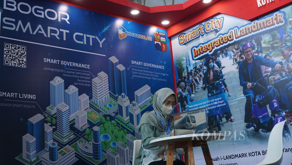 Seorang petugas berjaga pada<i> booth</i> yang dipamerkannya dalam acara Indo Smart City 2022, di Solo Technopark, Kota Surakarta, Jawa Tengah, Rabu (12/10/2022). Forum diskusi tersebut membahas penerapan kota pintar bagi daerah-daerah.