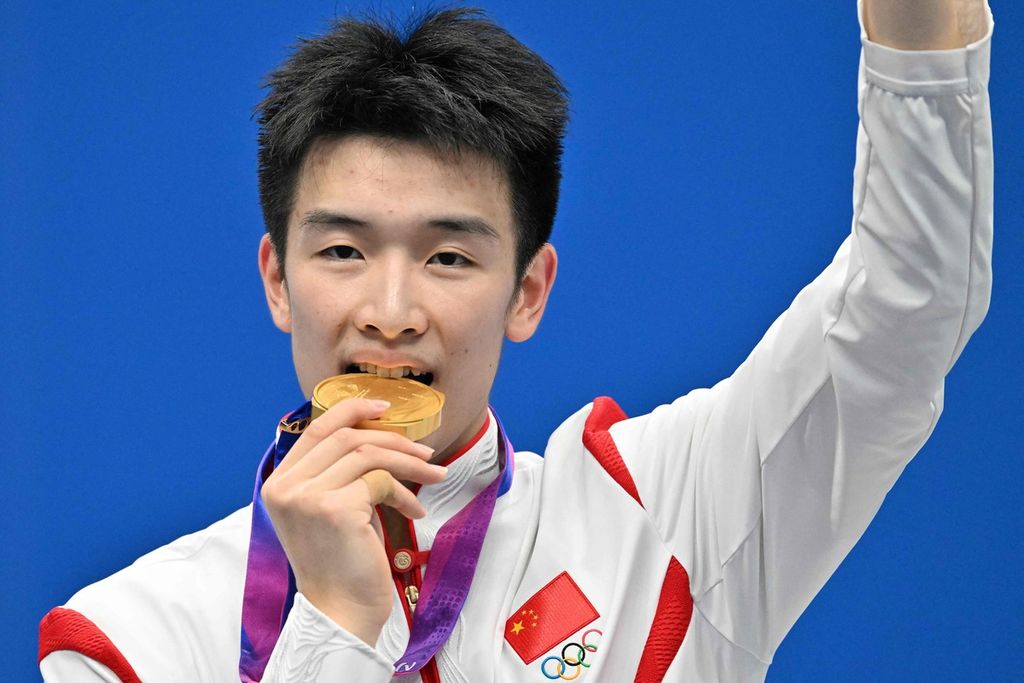 Peraih medali emas bulu tangkis tunggal putra Asian Games Hangzhou 2022, Li Shifeng (China), menggigit medalinya seusai upacara penyerahan medali di Binjiang Gymnasium Hangzhou, Sabtu (7/10/2023). 