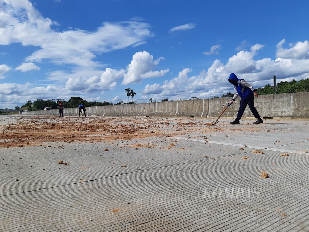 Petugas membersihkan Jalan Tol Balikpapan-Samarinda Kilometer 6 di Kalimantan Timur, Rabu (2/3/2022).
