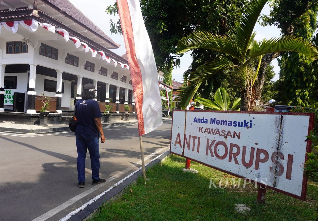 Wartawan melintas di dekat papan bertuliskan kawasan antikorupsi di sekitar Kantor Bupati Pemalang, Jawa Tengah, Jumat (12/8/2022). 