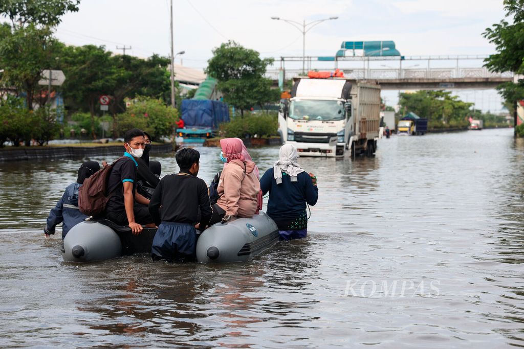 Petugas mengantarkan warga menggunakan perahu karet untuk menghindari banjir yang menggenangi Kaligawe, Kota Semarang, Jawa Tengah, Senin (2/1/2023).