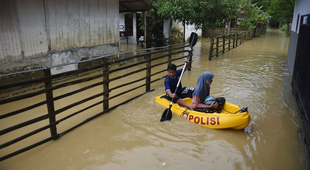 Warga menaiki kano saat banjir di Desa Blega, Kecamatan Blega, Kabupaten Bangkalan, Jatim, Minggu (1/1/2023). 