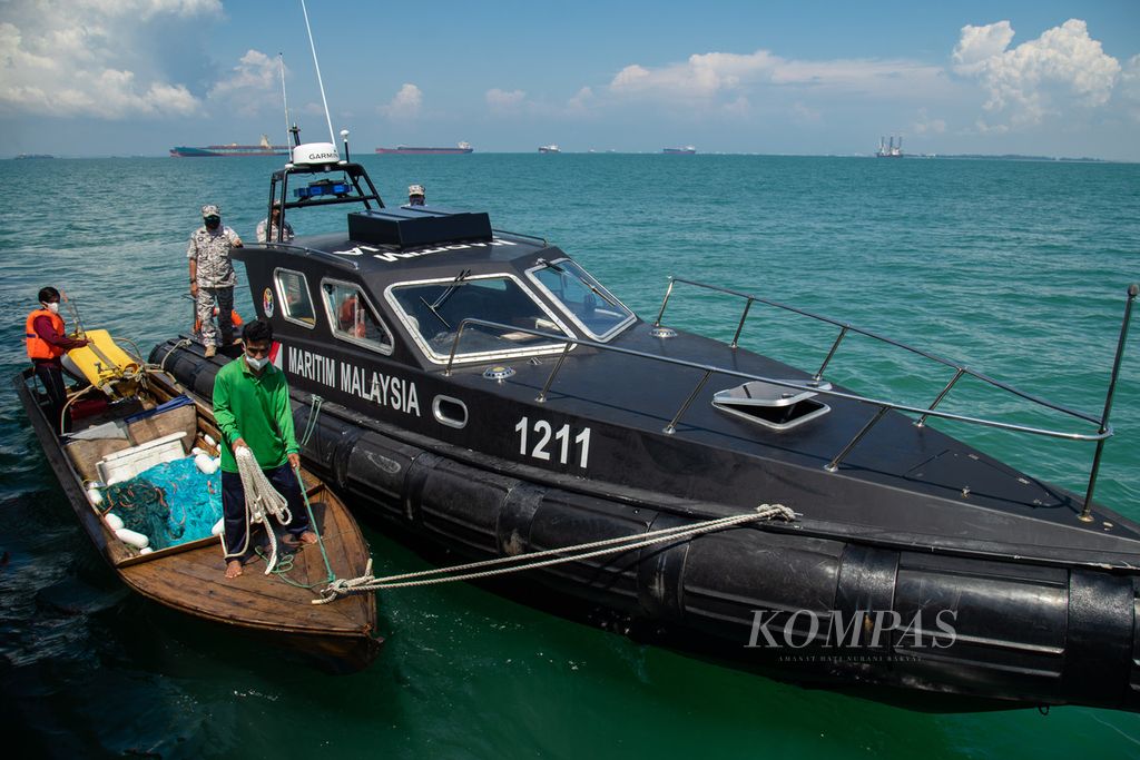 Dua nelayan asal Batam, Kepulauan Riau, didampingi Agensi Penguatkuasaan Maritim Malaysia (APMM) bersiap merapat ke Kapal Negara Bintang Laut milik Badan Keamanan Laut (Bakamla) Republik Indonesia di perairan Pengerang, Malaysia, Senin (26/4/2021). 