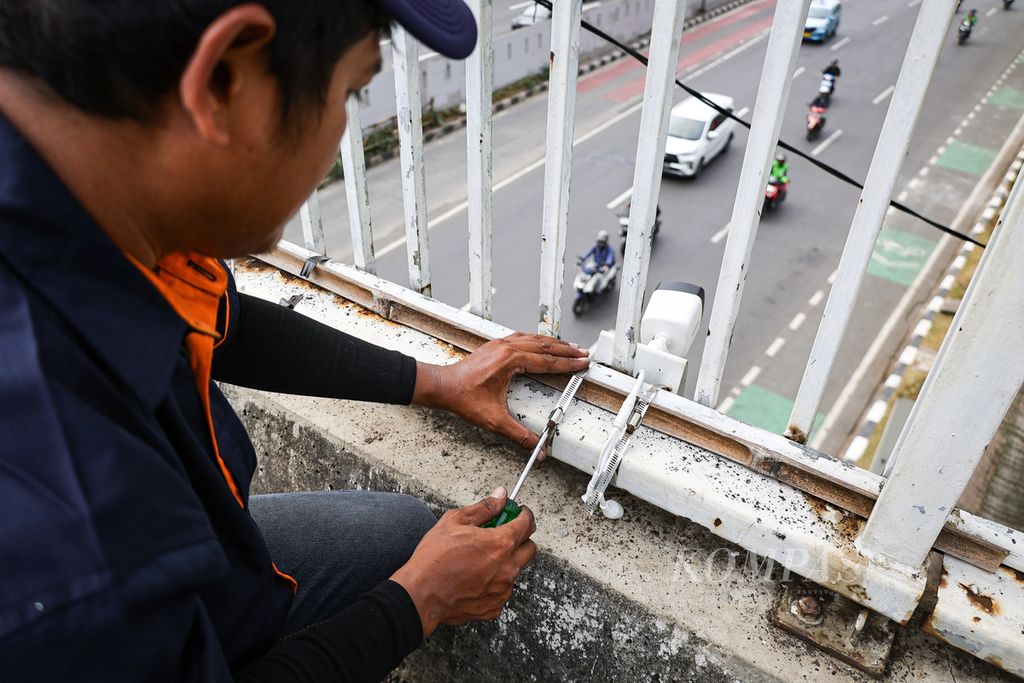 Petugas memperbaiki CCTV yang rusak di jembatan penyeberangan orang di depan Kompleks Parlemen, Jakarta, Jumat (23/8/2024).