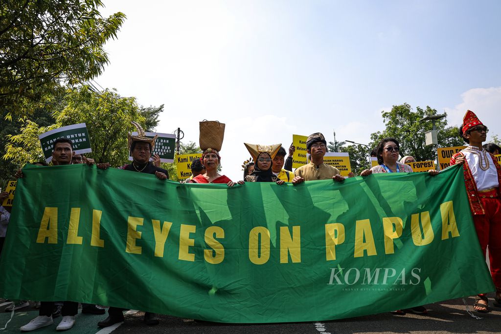 Aktivis berpakaian daerah membentangkan spanduk dukungan kepada masyarakat adat suku Awyu dan Moi dari Papua di depan Gedung Mahkamah Agung, Jakarta, 22 Juli 2024.