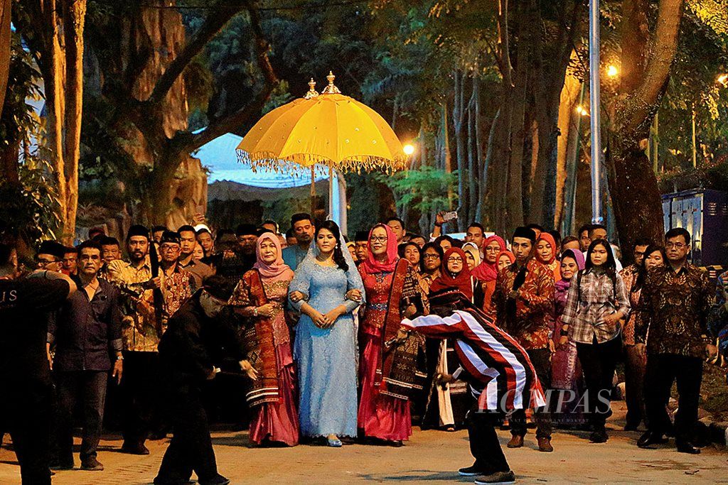 Putri Presiden Joko Widodo, Kahiyang Ayu (berkebaya biru), dituntun mertuanya, Ade Hanifah Siregar (sebelah kanan Kahiyang), masuk ke rumah mertuanya di Taman Setia Budi Indah, Medan, Sumatera Utara, Minggu (19/11). Bobby  Nasution, suami Kahiyang, berjalan  di belakangnya. Mereka menjalani  haroan boru,  acara penyambutan kedatangan pertama mempelai perempuan ke rumah mempelai laki-laki. 