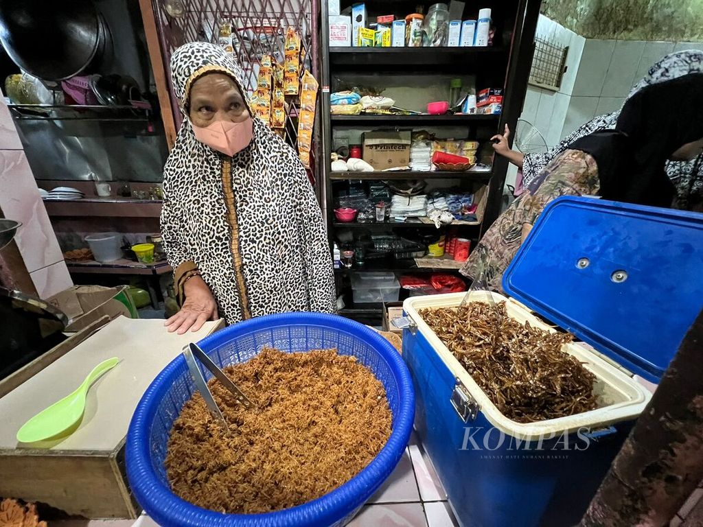 Hj Haniah (60) menyiapkan kelapa sangrai dan ikan teri kering digoreng garing untuk pelengkap Songkolo Bagadang di warungnya di Antang, Makassar, Sulsel, Sabtu (9/4/2022).