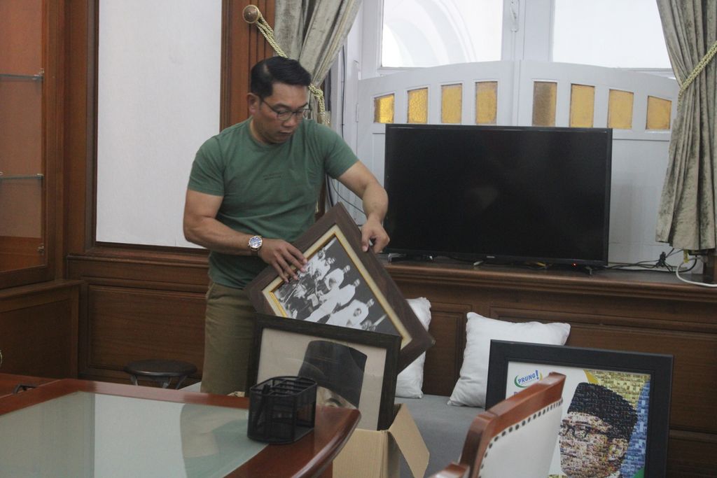 Ridwan Kamil melepas dan merapikan foto-foto yang dipajang di ruang kerjanya, sayap timur Gedung Pakuan, Kota Bandung, Jawa Barat, Selasa (29/8/2023).