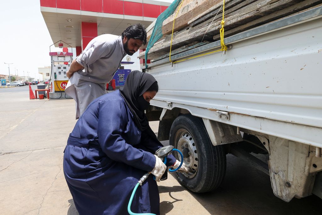 Ghada Ahmad (kanan) tengah memeriksa tekanan angin ban mobil milik pelanggan bengkel Petromin Express di Jeddah, Arab Saudi, Kamis (26/5/2022). Ahmad bersama sejumlah pekerja perempuan kini memiliki cukup kebebasan untuk bekerja di bengkel, sebagai montir, sebuah hal yang dulu hanya bisa dikerjakan oleh laki-laki. 