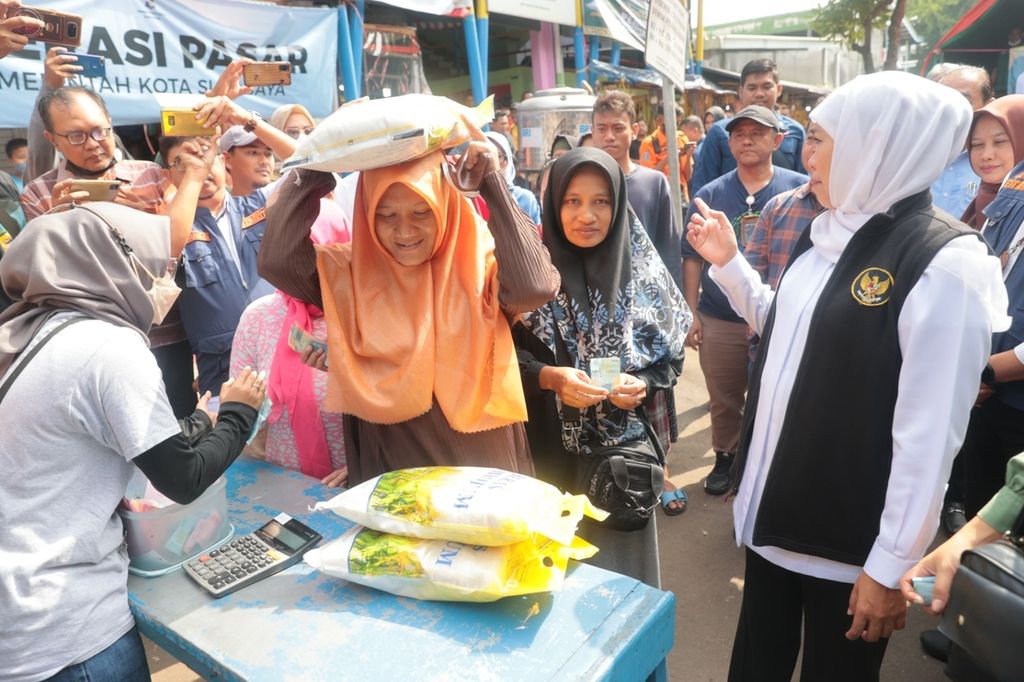 Gubernur Jatim Khofifah Indar Parawansa menyapa warga yang antusias membeli beras dalam operasi pasar di Pasar Pucang Anom, Surabaya, Sabtu (4/2/2023). Beras medium dijual Rp 46.000 per kemasan 5 kilogram (kg), jauh lebih murah dari harga pasaran Rp 60.000 per kg. 