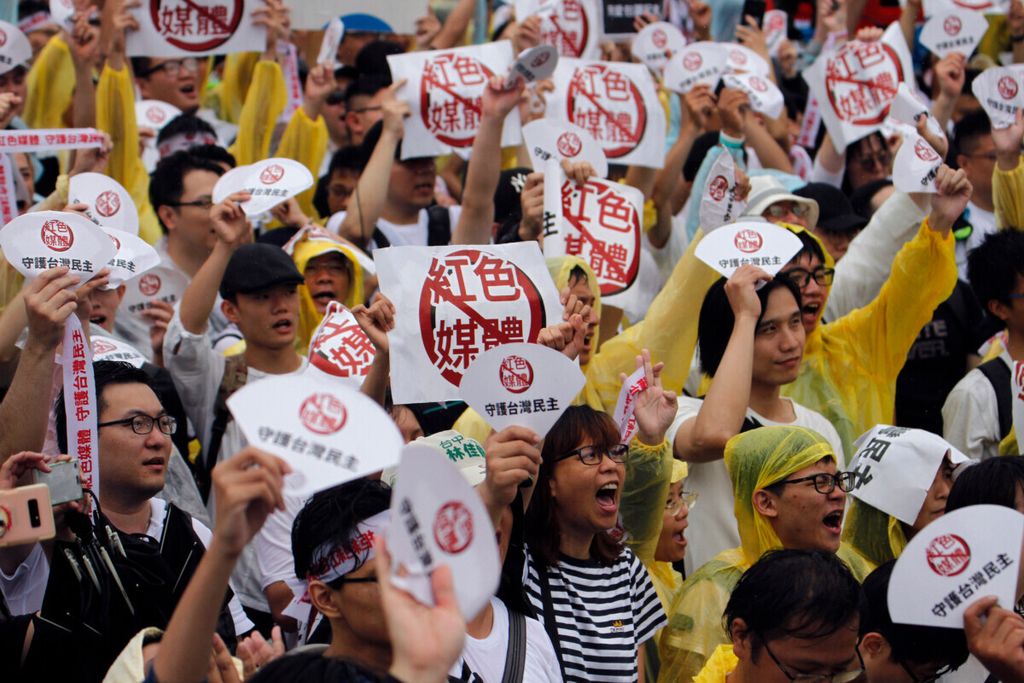 Dalam foto yang diambil pada 23 Juni 2019 ini, para demonstran memegang plakat dengan pesan bertuliskan Tolak Media Merah” dan ”Jaga Demokrasi Negara” menentang media pro-China di depan gedung Kantor Kepresidenan di Taipei, Taiwan. 