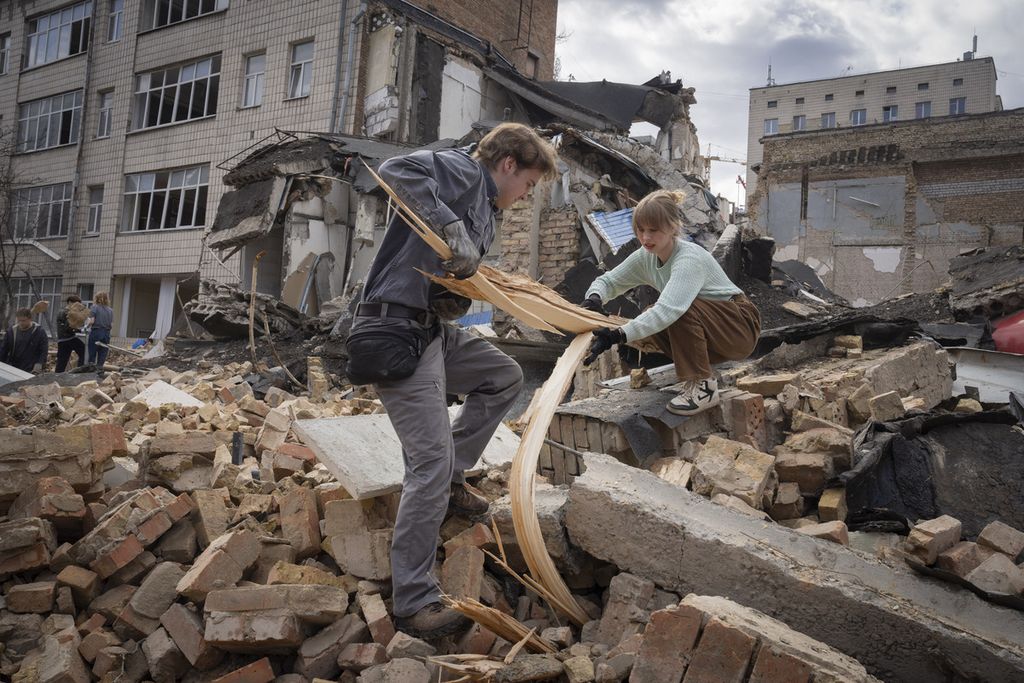 Sukarelawan membersihkan puing-puing bangunan dampak serangan Rusia terhadap Akademi Seni Kyiv, Ukraina, Sabtu (30/3/2024).