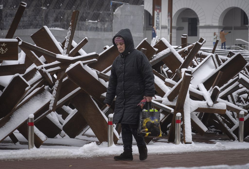 Seorang perempuan warga Ukraina berjalan di depan barikade antitank di pusat kota Kyiv, Ukraina, Senin (12/12/2022). Presiden Ukraina Vladymyr Zelenskyy kembali menyerukan agar militer Rusia menghentikan invasinya dan segera meninggalkan wilayah Ukraina. 
