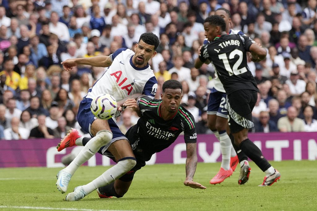 Pemain Tottenham Hotspur, Dominic Solanke (kiri), berebut bola dengan pemain Arsenal, Gabriel (tengah), pada laga Liga Inggris di London, Sabtu (15/9/2024). Arsenal memenangi laga itu dengan skor 1-0. 