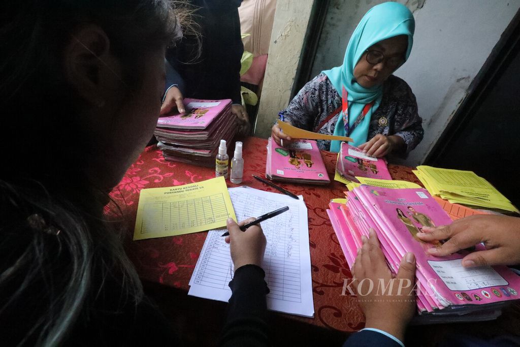 Petugas kader posyandu melayani pendaftaran para ibu-ibu yang berkunjung untuk pemeriksaan rutin anak-anak mereka di Posyandu RW 005 Rawa Terate, Cakung, Jakarta Timur , Selasa (14/2/2023).