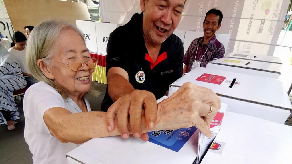 Seorang lansia, Dien (83) dibantu anaknya memasukkan kertas suara yang sudah dicoblos usai mengunakan hak pilihnya di TPS 073, Rw 04 Kelurahan Joglo, Kembangan, Jakarta, Rabu (17/4/2019). Tua muda tak terkecuali menunjukkan antusiasme mengikuti Pemilu 2019.