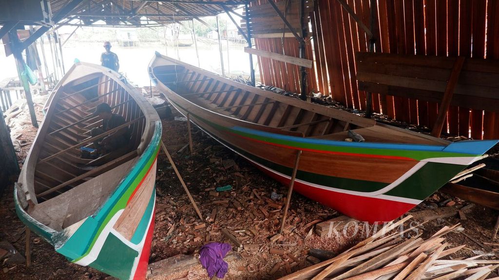 Dua tukang mengerjakan proses akhir pembuatan perahu di Desa Pulau Sewangi, Kecamatan Alalak, Kabupaten Barito Kuala, Kalimantan Selatan, Sabtu (9/3/2024). 