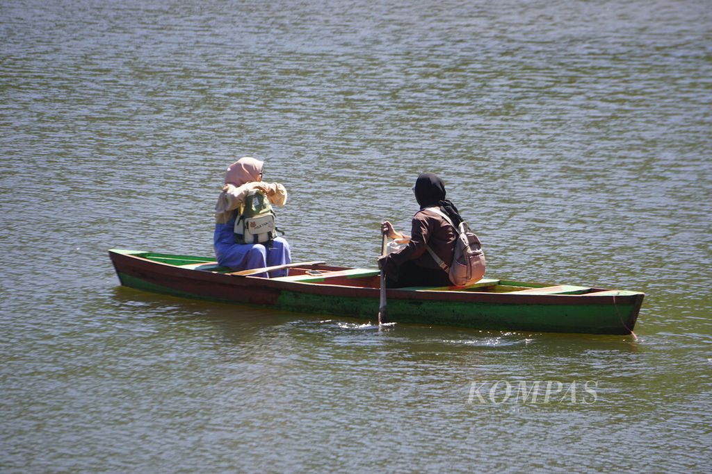 Pengunjung mendayung perahu menikmati suasana Telaga Kumpe di Desa Gununglurah, Kecamatan Cilongok, Kabupaten Banyumas, Jawa Tengah, Rabu (12/7/2023).
