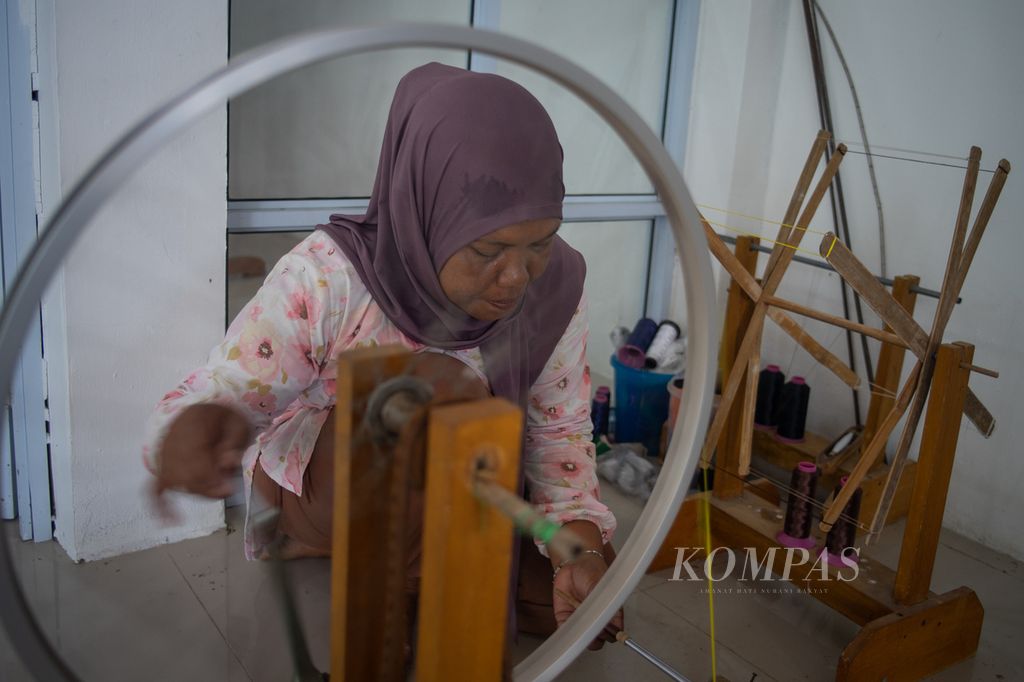 Suhana menggulung benang untuk menenun kain di Pulau Ngenang, Kota Batam, Kepulauan Riau, Kamis (14/12/2023).