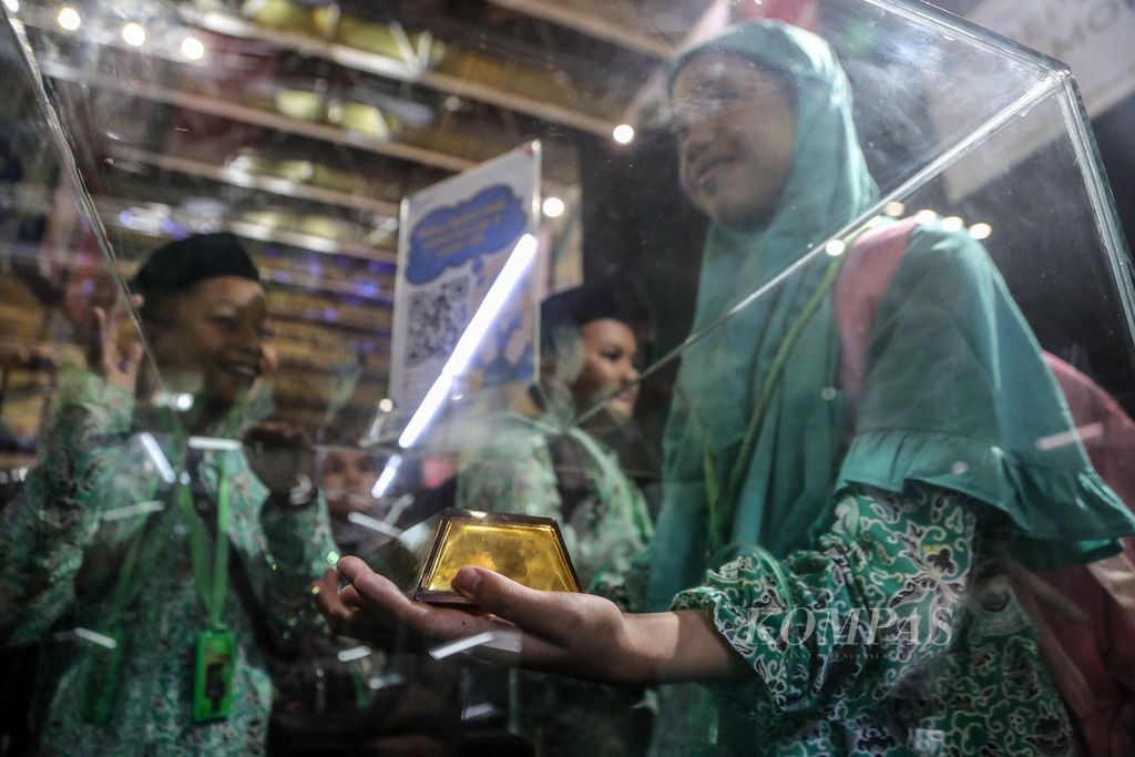 Seorang siswi mengangkat replika emas batangan yang dipamerkan di Festival Rupiah Berdaulat Indonesia 2023 di Istora Senayan, kompleks Gelora Bung Karno, Jakarta, Sabtu (19/8/2023). 
