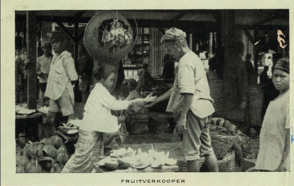 Seorang anak perempuan memberikan uang kepada pria bumiputra penjual buah di sebuah pasar sekitar abad ke-20. (Sumber: KITLV Leiden) 