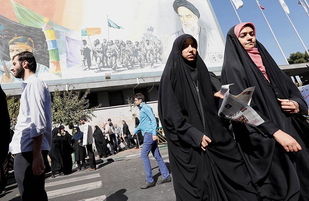 Warga Teheran melintas di depan poster bergambar mendiang Pemimpin Iran Ayatollah Khomeini di Teheran, Iran, Jumat (13/10), menjelang pidato Presiden Amerika Serikat Donald Trump yang akan menyampaikan strategi lebih agresif untuk menekan program nuklir Iran pada Sabtu dini hari WIB. 