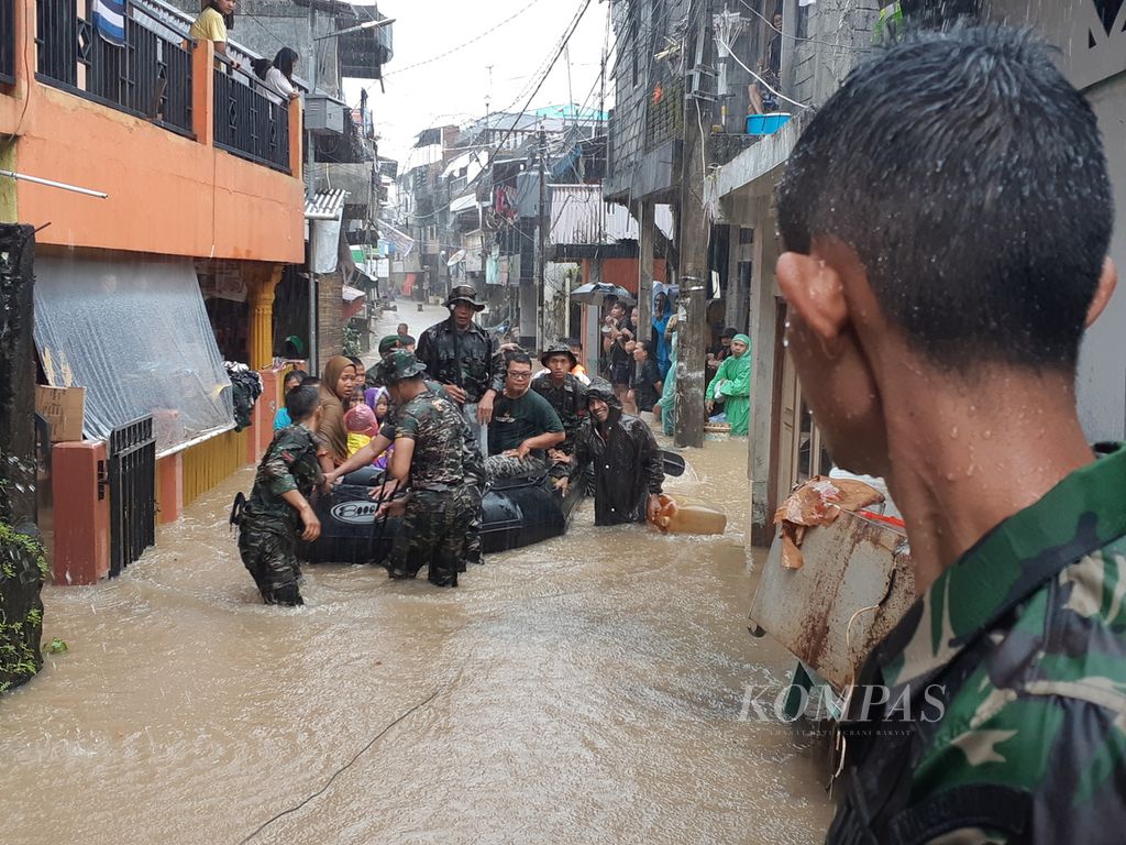 Pasukan Komando Resor Militer 131/Santiago mengevakuasi warga dengan perahu karet, Jumat (27/1/2023), di Kelurahan Komo Luar, Manado, Sulawesi Utara. Hujan deras yang mengguyur sejak dini hingga sore hari menyebabkan banjir dan tanah longsor di 23 kelurahan yang tersebar di delapan kecamatan.