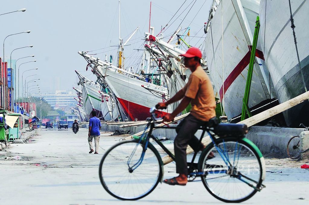 Ojek sepeda tengah melintas di depan deretan kapal barang tradisional di Pelabuhan Sunda Kelapa, Jakarta Utara.